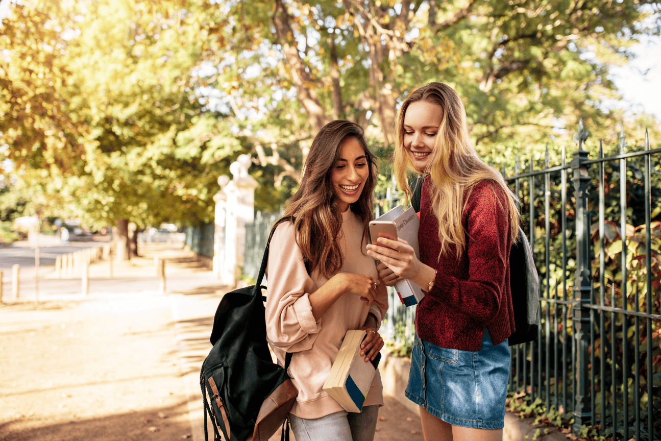 Students smiling and using mobile device